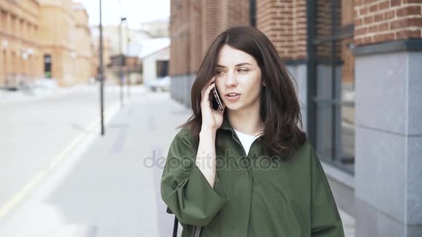 Menina encantadora em uma camisa verde falando no telefone na rua, vista frontal — Vídeo de Stock