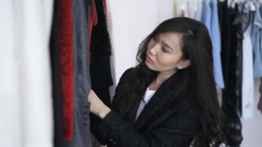 Çekici Asyalı genç kadın bir dükkanda kış giysiler seçmek