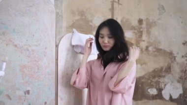 Asyalı kadın beyaz kot pantolon geniş pembe gömlek bir dükkanda üzerinde çalışıyor