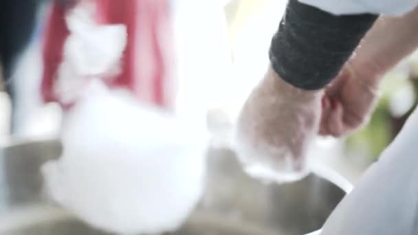Mujer haciendo algodón de azúcar en la feria infantil y dándoselo a una chica — Vídeo de stock