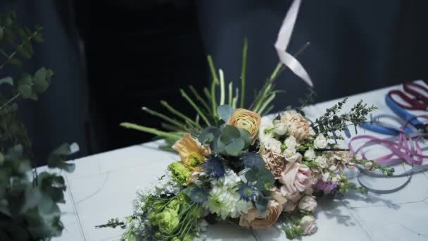 Florista assistente loja combinando uma fita para um monte de flores — Vídeo de Stock