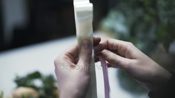 Close up of flower shop assistant making a ribbon decoration — Stock Video