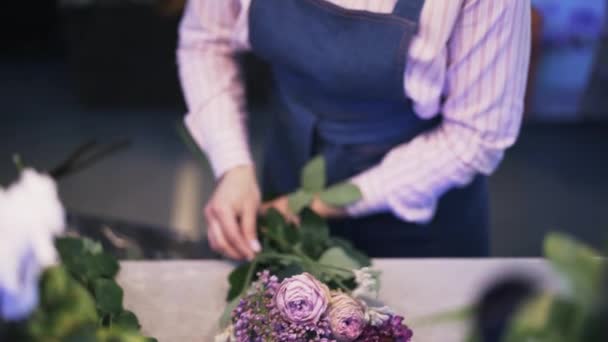 Primer plano de una florista mujer haciendo un ramo de flores púrpura, inclinar hacia abajo — Vídeos de Stock