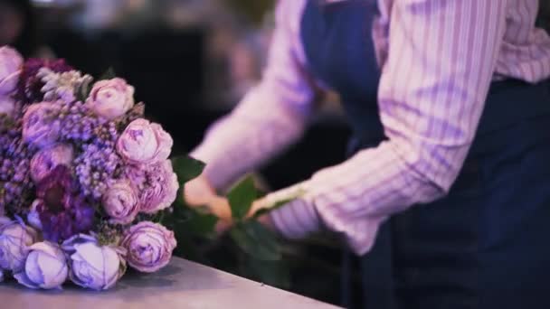 Vue latérale d'une fleuriste femme faisant un bouquet violet, panoramique — Video