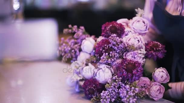 Vista lateral de una florista mujer haciendo un ramo púrpura — Vídeo de stock