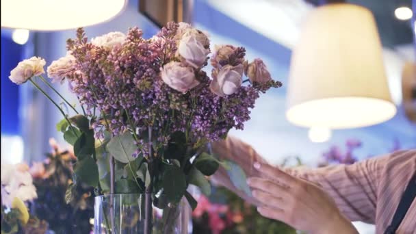 Virágárus shop munkavállaló elhelyezés rózsaszín és fehér virágok a vázában — Stock videók