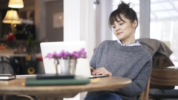 Genç kadın bir kafede onu laptop ile iyi vakit geçiriyor — Stok video