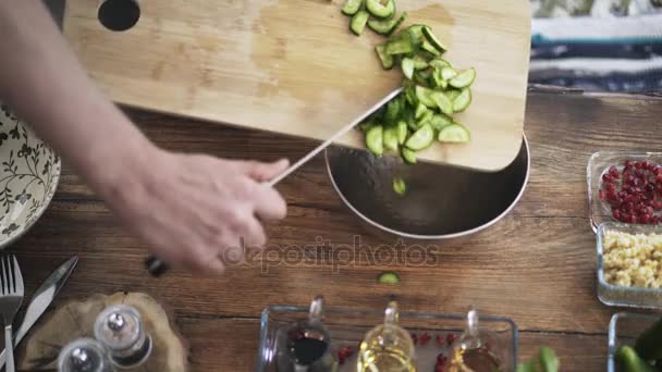 Bovenaanzicht van een chef-kok brengen gesneden komkommers in een metaalkom — Stockvideo