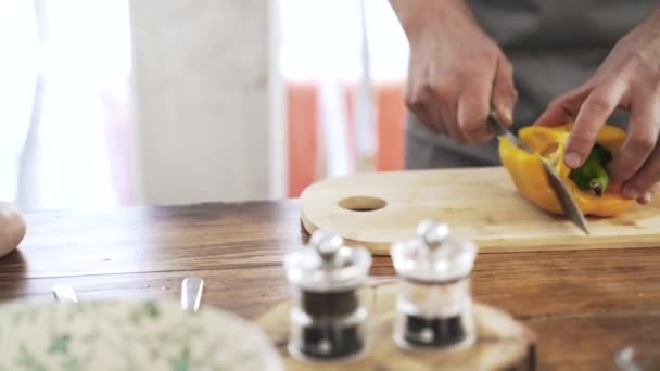 Panela tiro de um chef cortando um pimentão amarelo em uma tábua de madeira — Vídeo de Stock