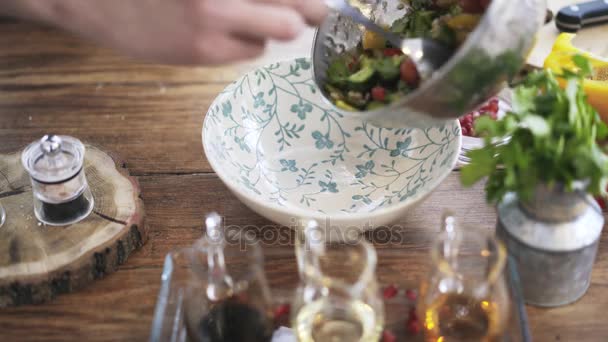 Chef poniendo una ensalada de verduras de un tazón de metal en un plato — Vídeo de stock