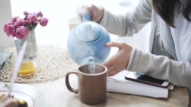 Pan shot of a woman pouring tea for her friend eating vegetables in a cafe — Stock Video