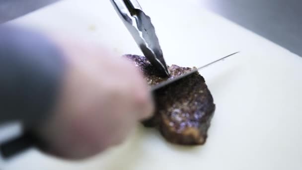 Nahaufnahme eines Chefs, der ein gebratenes Steak in Scheiben schneidet — Stockvideo