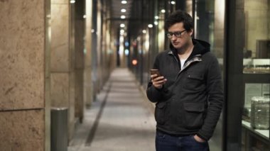 Gece sokakta onun smartphone kullanarak gözlüklü genç adam