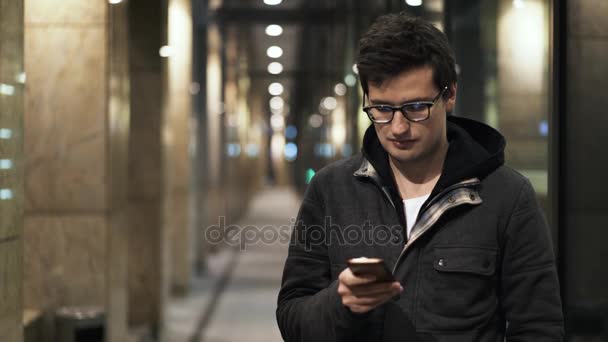 Joven hombre mensajes de texto en la calle por la noche — Vídeos de Stock