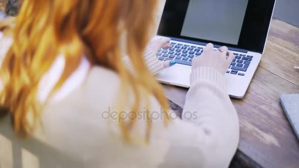 Vista trasera de una joven pelirroja escribiendo en un parque — Vídeo de stock