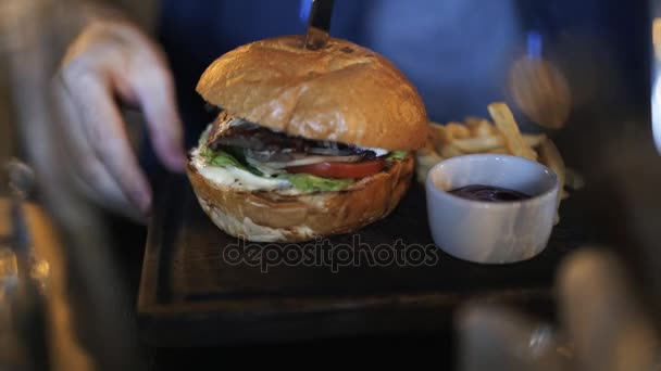 Közelről egy ember fog enni egy hamburger, hasábburgonyával — Stock videók