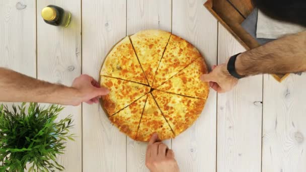 Vue du dessus des mains de trois hommes prenant des tranches de pizza — Video