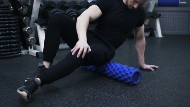 Primer plano del hombre trabajando con su nalga en un rollo en el gimnasio — Vídeo de stock