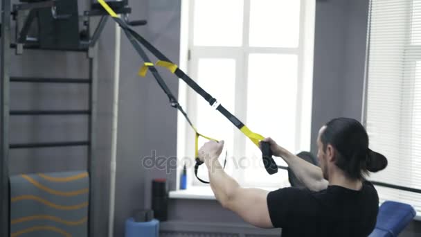Задний вид человека, делающего отжимания с гимнастическими кольцами — стоковое видео