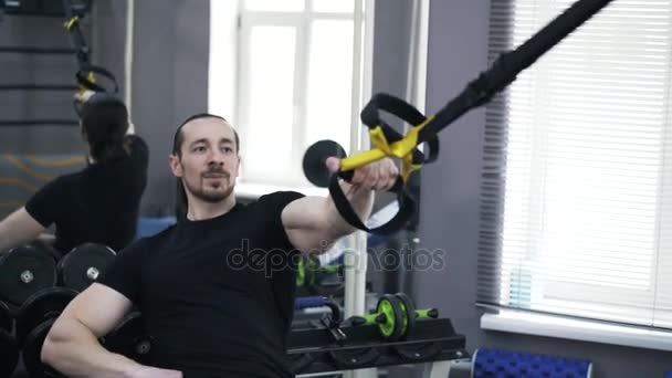 Vista frontal de un hombre haciendo flexiones de un brazo con anillos gimnásticos — Vídeos de Stock