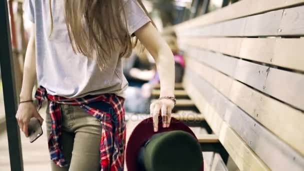 Mujer joven en ropa casual con un sombrero está marcando un número fuera — Vídeo de stock