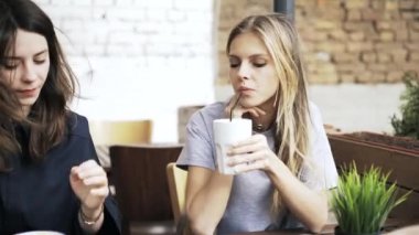 Bir akıllı telefon arayan ve içecekler içme bir kafede iki kız arkadaşım