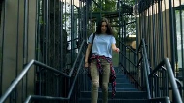 Kadın haki bir kot pantolon ve açık havada merdivenlerden bir T shirt