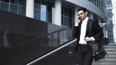 Aşağıda gidiyor ve telefonda konuşurken gözlüklü genç yakışıklı işadamı