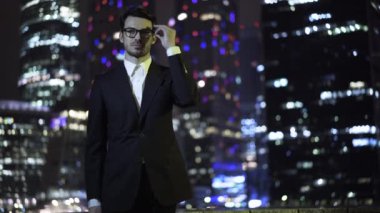 Gözlüklerini koyarak ve cityscape geceleri arıyorum genç işadamı yakın çekim