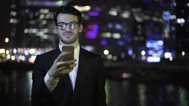 Vista frontal de un hombre de negocios web surf, rascacielos fondo — Vídeo de stock