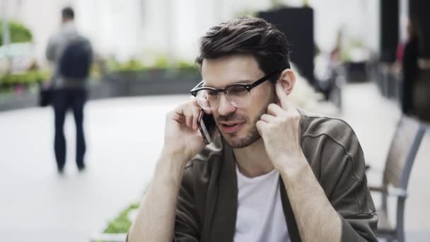 Retrato de un hipster con gafas en un teléfono en un café — Vídeos de Stock