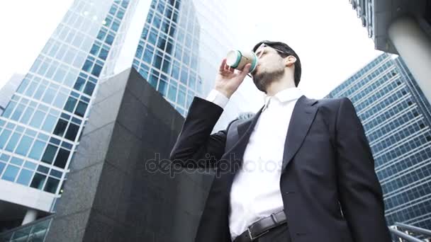Gros plan d'un jeune homme d'affaires en lunettes buvant du café dans un centre-ville — Video