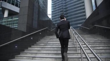 Young businessman in a suit going upstairs and talking on the phone