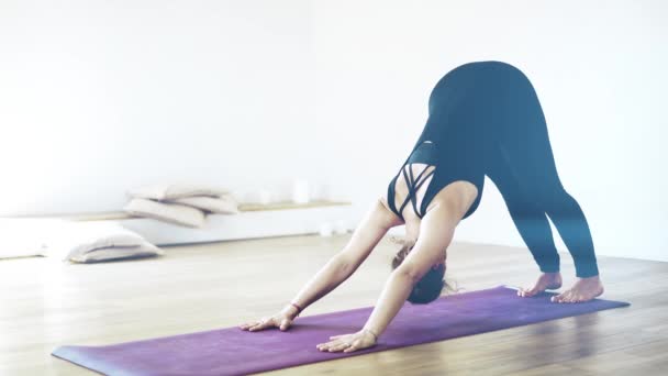 Porträt einer hübschen Frau in Schwarz, die drinnen Yoga macht, aus nächster Nähe — Stockvideo