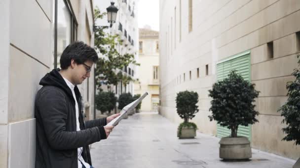 Bir harita bir Valencia sokakta okuyan genç bir adam yan görünüm — Stok video