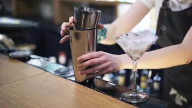 Bir shaker buz koyarak ve suyu ekleyerek barmen