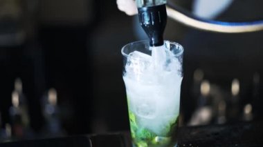 Bir kokteyl için su ekleyerek ve karıştırarak barmen