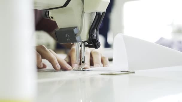 Close up de uma mulher costurando uma camisa branca em uma fábrica — Vídeo de Stock