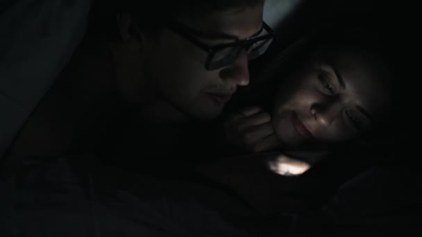 Paar in een donkere kamer met een smartphone — Stockvideo