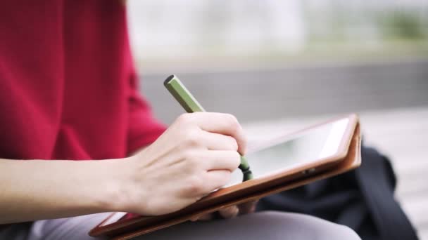 Крупный план девушки в красном, работающей на планшете специальной ручкой — стоковое видео