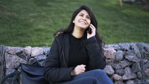 Красивая молодая женщина разговаривает по телефону в парке — стоковое видео