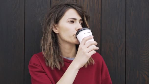 Ung kvinna i en sweatshirt med en kopp kaffe, närbild — Stockvideo