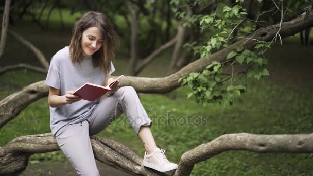 Junge Frau liest in einem Park ein Buch — Stockvideo