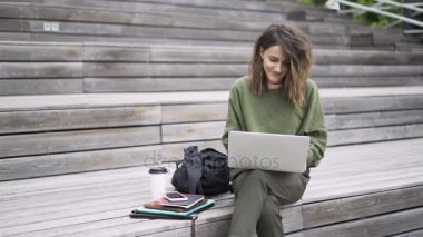 Laptop dışında yazarak yeşil kazaklı genç kadın