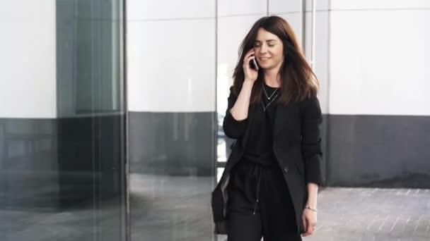 Красивая молодая деловая женщина разговаривает по телефону и ходит — стоковое видео