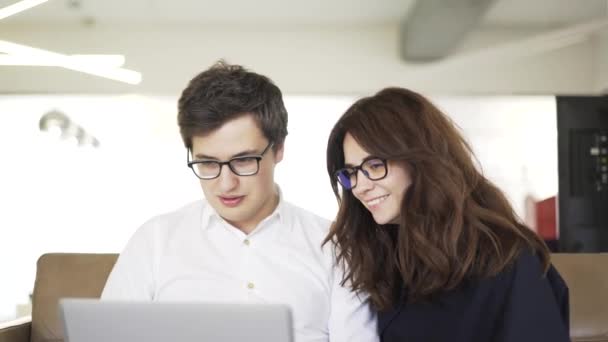 Young couple of business people on coach with a laptop — Stock Video