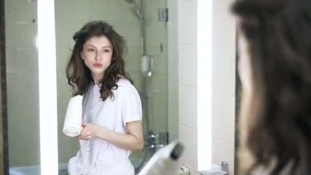 Jovem mulher cantando em seu secador de cabelo no banheiro — Vídeo de Stock