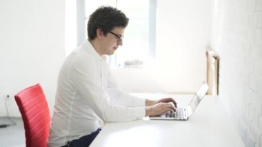 Ofiste onun laptop klavye yazarak bir genç işadamı yan görünüm