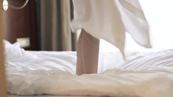 Вид збоку на жіночі ноги, що підстрибують на ліжку, повільний рух — стокове відео