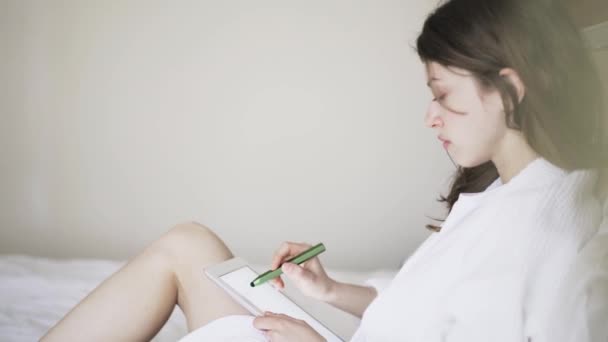 Jeune fille dessin sur sa tablette dans le lit, vue latérale — Video